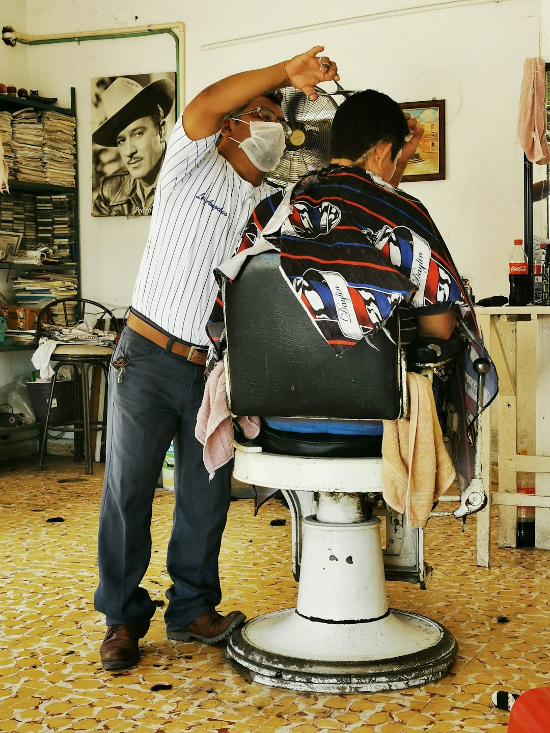 Mobiler Friseur bei der Arbeit an den Haaren eines Kunden.